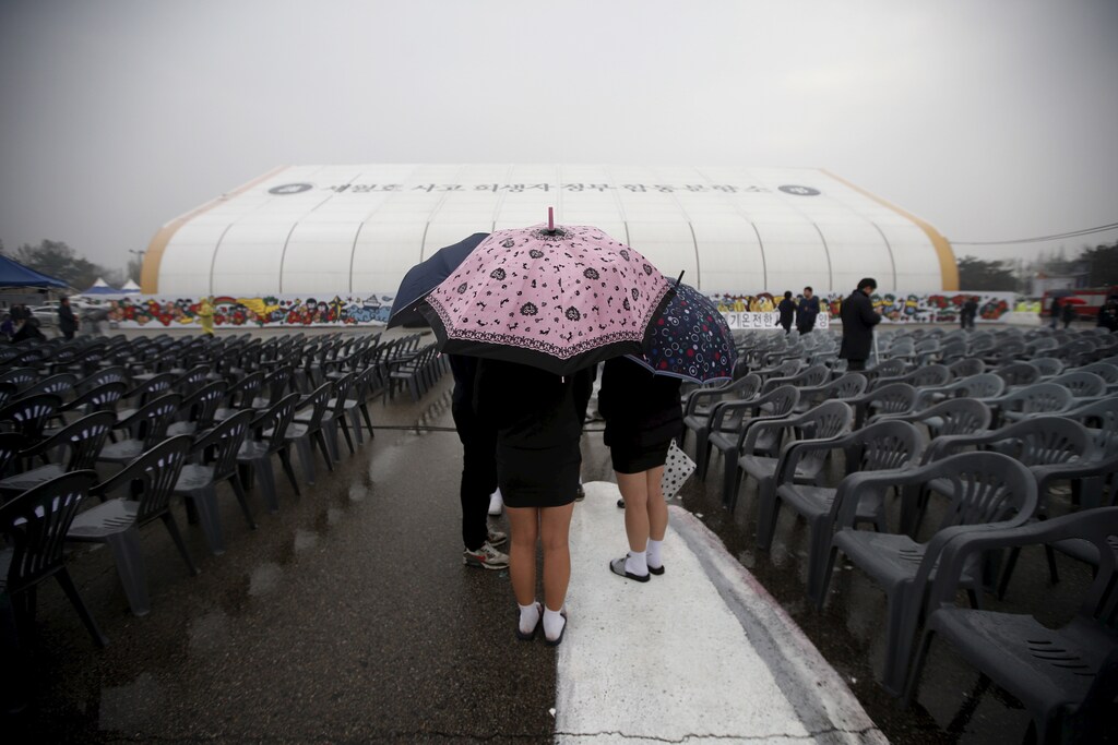 Students holding umbrellas visit the official memorial altar for the victims of the ferry disaster that killed more than 300 passengers on the occasion of the first anniversary, in Ansan April 16, 2015. REUTERS/Kim Hong-Ji - GF10000060875