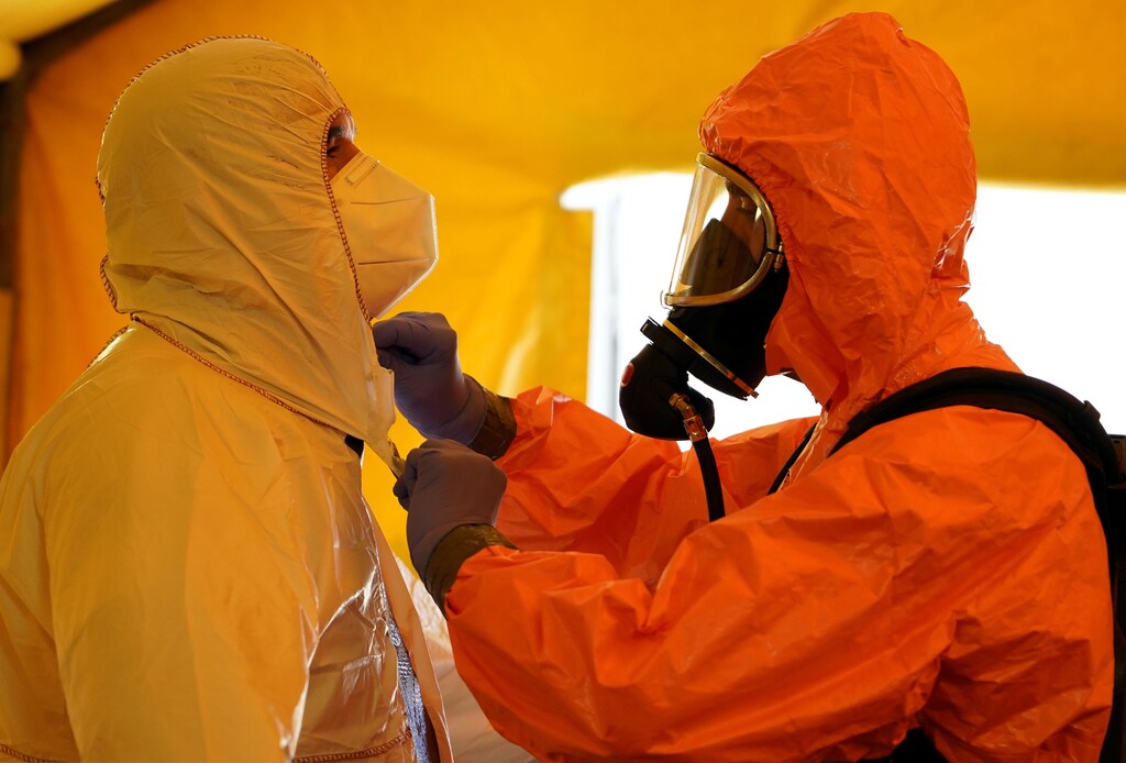 A member of Madrid's SAMUR Ambulance Service adjusts protective gear of his colleague, during the coronavirus disease (COVID-19) pandemic, at their headquarters in Madrid, Spain, August 26, 2020. Picture taken August 26, 2020. REUTERS/Juan Medina - RC28MI929BW8