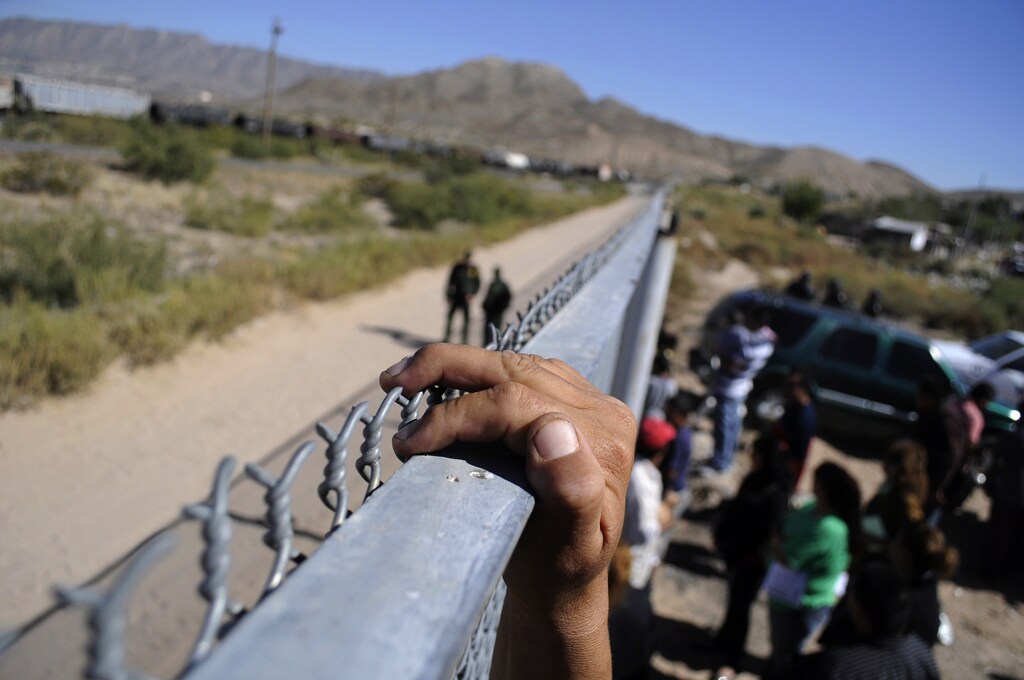 A person holds onto the fence marking the border between the United States and Mexico in Ciudad Juarez November 2, 2010.