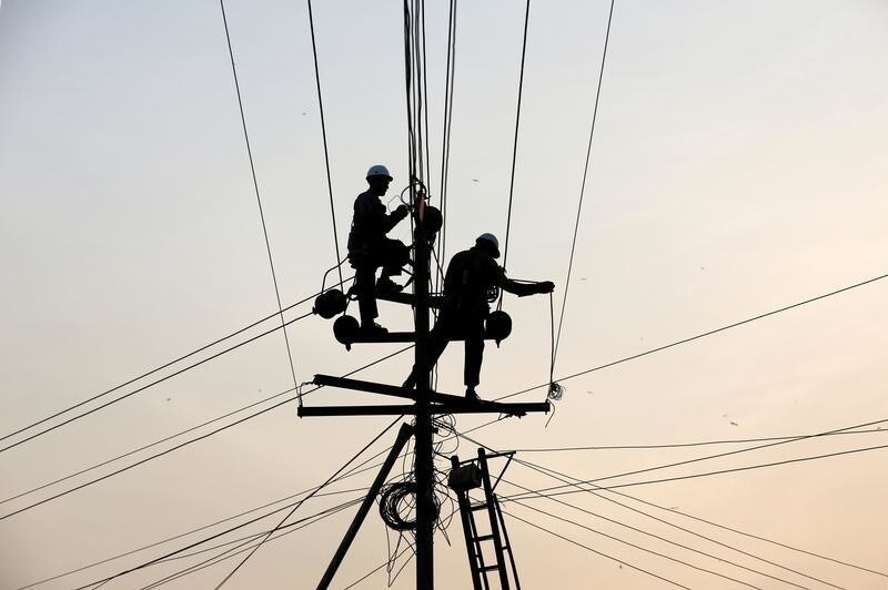 Technicians are silhouetted as they fix cables on a power transmission line in Karachi, Pakistan, January 9, 2017. REUTERS/Akhtar Soomro