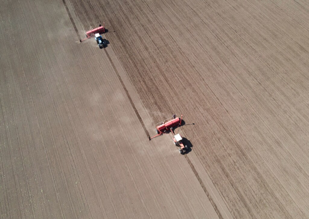 Agricultural workers operate tractors with seeders to sow soybeans in a Ukraine field.