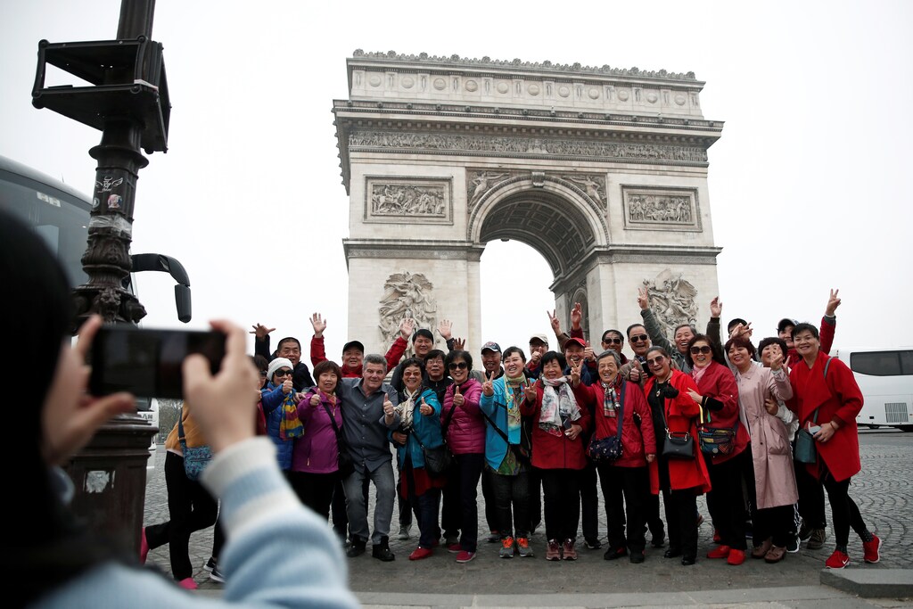 Chinese tourists pose for photos in front of the Arc de Triomphe on the Champs-Elysees avenue during the Act XIX (the 19th consecutive national protest on a Saturday) of the "yellow vests" movement in Paris, France, March 23, 2019. REUTERS/Benoit Tessier - RC1CAD5A0980
