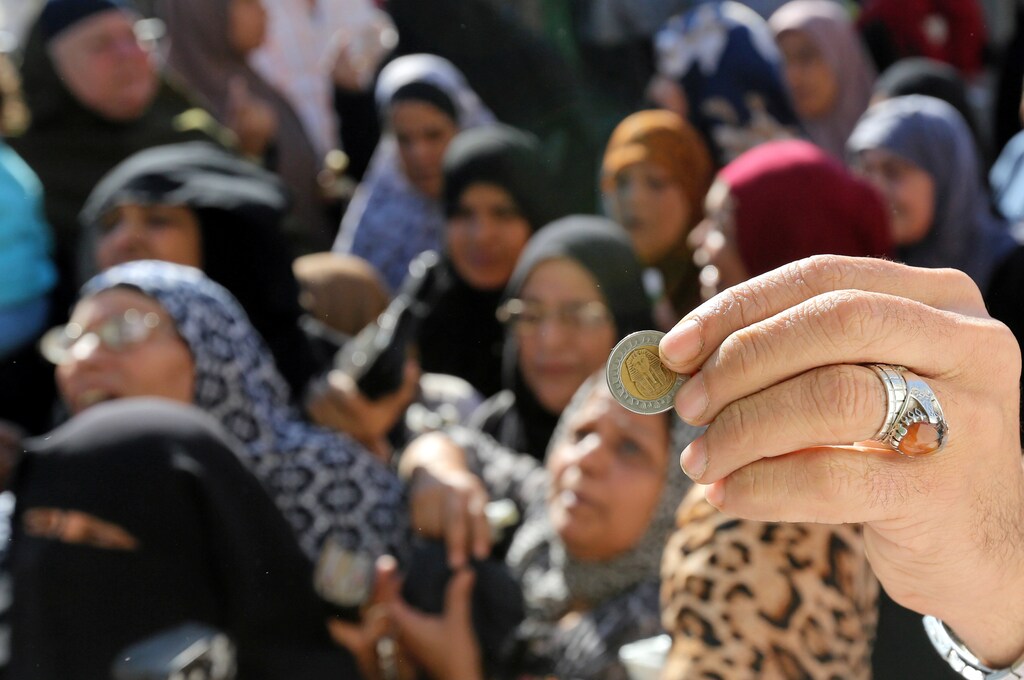 An Egyptian man holds a one pound coin to buy sugar from a government truck, after goods shortage in retail stores across the country and after the central bank floated the pound currency, in downtown Cairo, Egypt, November 7, 2016. REUTERS/Mohamed Abd El Ghany - RTX2SCSQ