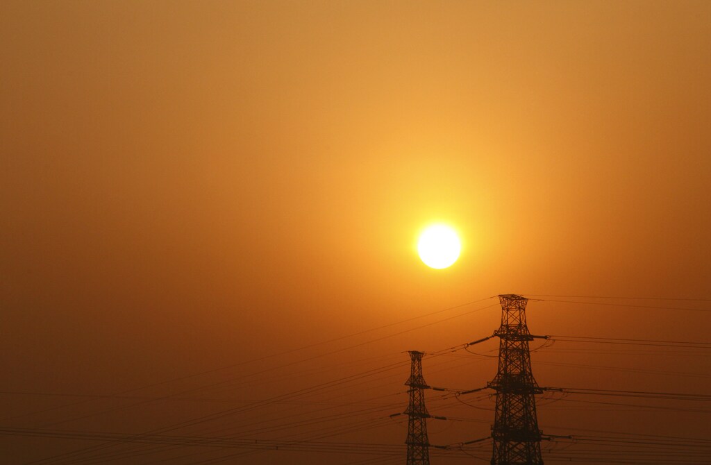 The sun rises behind electricity pylons in Beijing