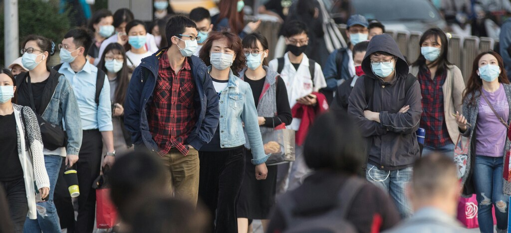 People cross a busy street wearing face masks; air pollution
