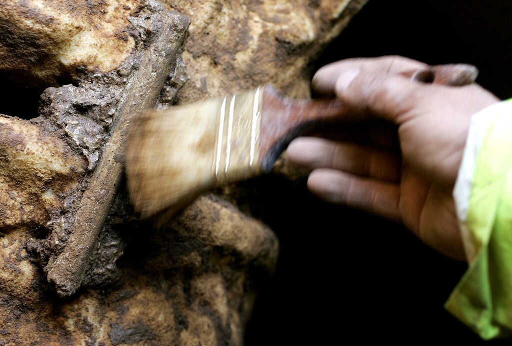 A worker cleans a sealed sarcophagi inside a Roman burial ground on the outskirts of Rome December 6, 2005. Italian archaeologists unveiled on Tuesday a Roman burial ground, complete with sealed marble sarcophagi, recently discovered in a stretch of bleak wasteland overlooked by a chicken processing factory.