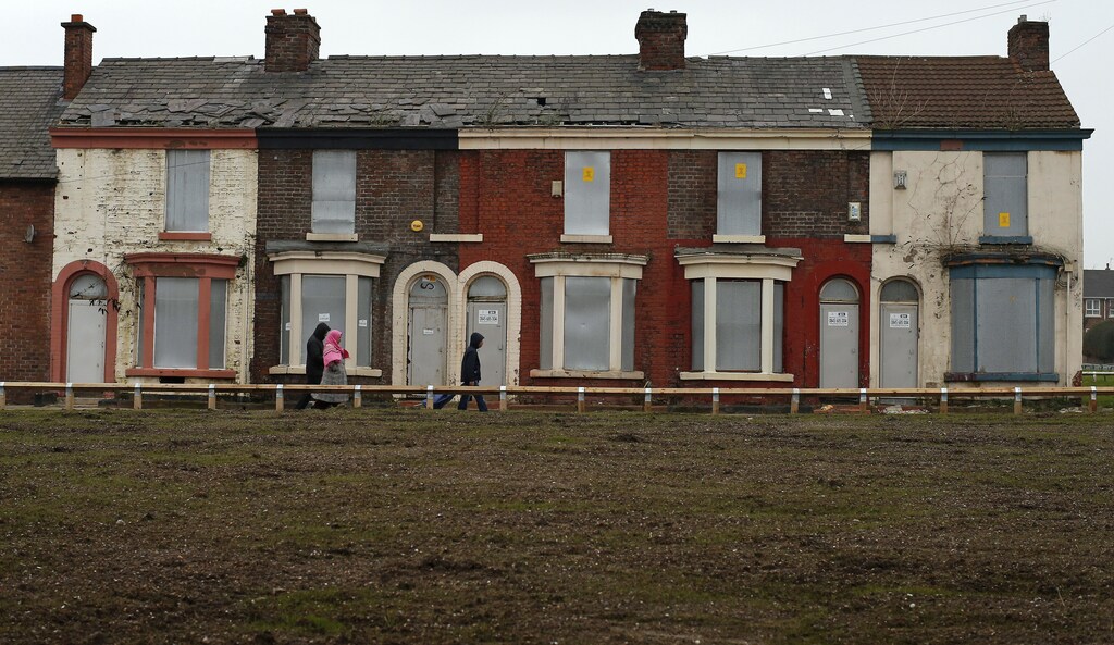 People walk past a row of boarded up terraced houses in the Kensington area of Liverpool, northern England February 20, 2013. REUTERS/Phil Noble