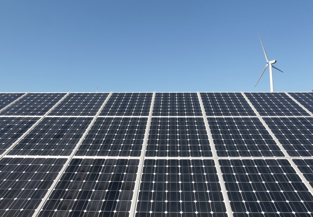 A wind turbine seen over solar power plant panels in Incheon, South Korea, highlighting renewable energy efforts for Earth Day .