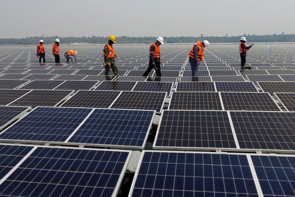Workers walk between solar cell panels