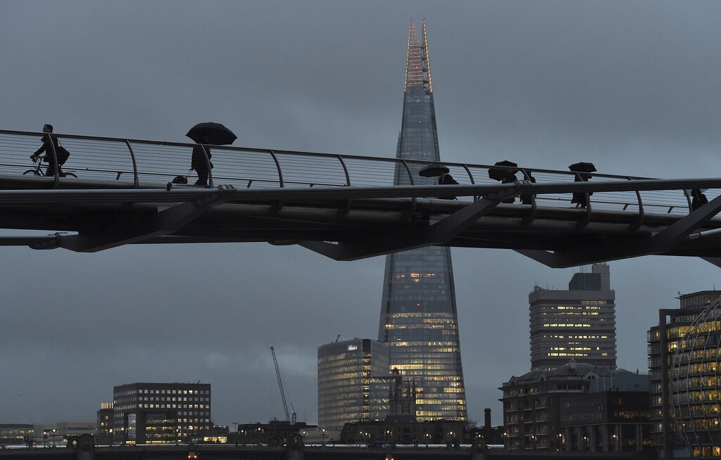 City workers cross the Millennium footbridge at dawn in front of the Shard skyscraper, in the financial district of London, Britain January 7, 2016.