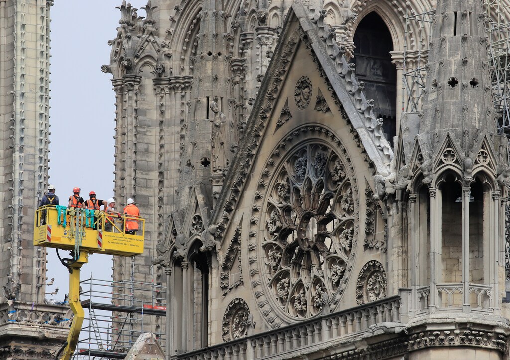 Men work to strengthen a part of Notre-Dame Cathedral, a week after a massive fire devastated large parts of the gothic structure in Paris, France, April 23, 2019. REUTERS/Gonzalo Fuentes - RC187EFF1C90