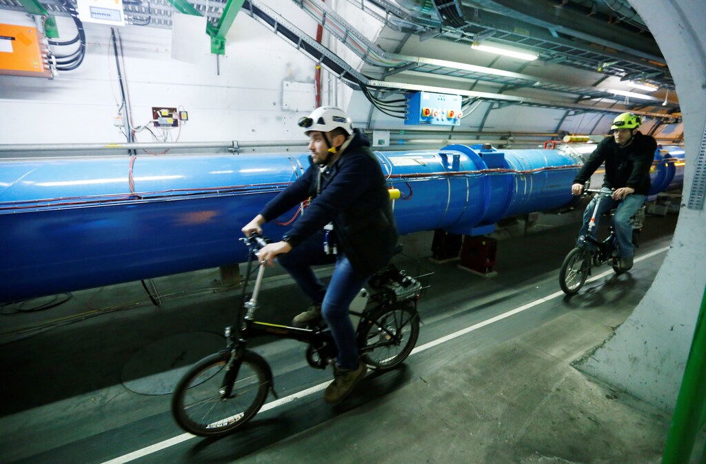 Scientists cycle along the Large Hadron Collider tunnel.