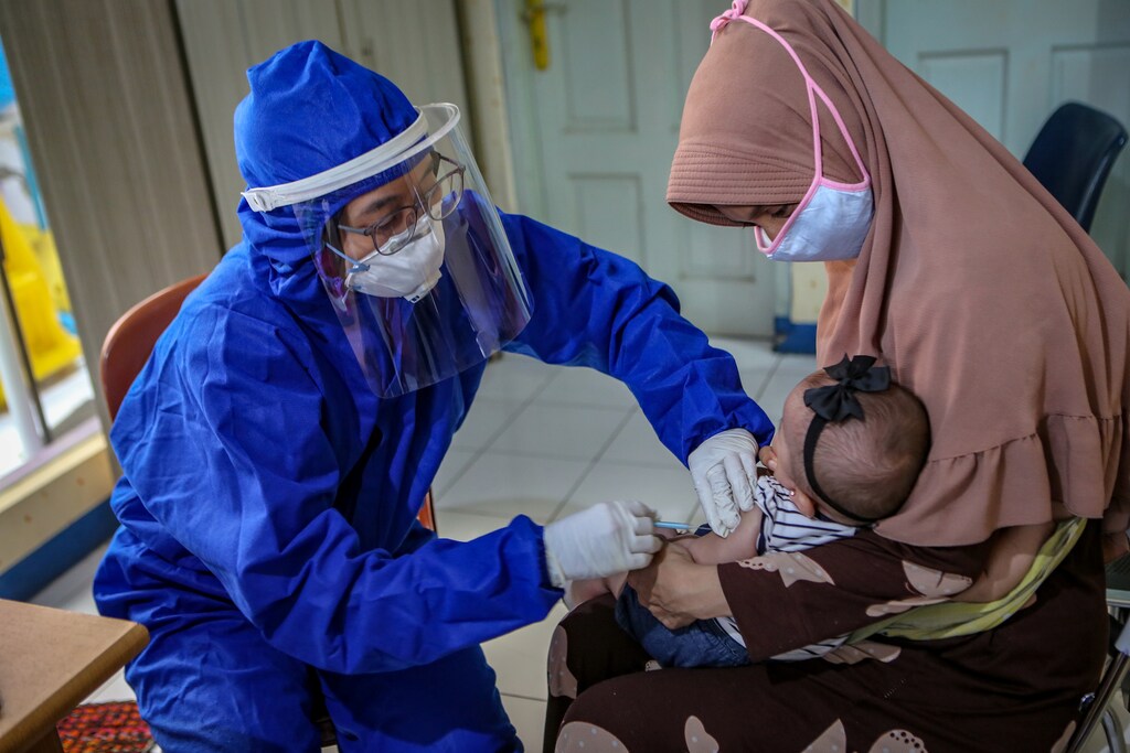 A medical staff member wearing personal protective equipment (PPE) vaccinates a baby, amid the coronavirus disease (COVID-19) outbreak, in Tangerang, near Jakarta, Indonesia May 13, 2020. Antara Foto/Fauzan/ via REUTERS ATTENTION EDITORS - THIS IMAGE HAS BEEN SUPPLIED BY A THIRD PARTY. MANDATORY CREDIT. INDONESIA OUT. NO COMMERCIAL OR EDITORIAL SALES IN INDONESIA. - RC2ONG9SDX7M