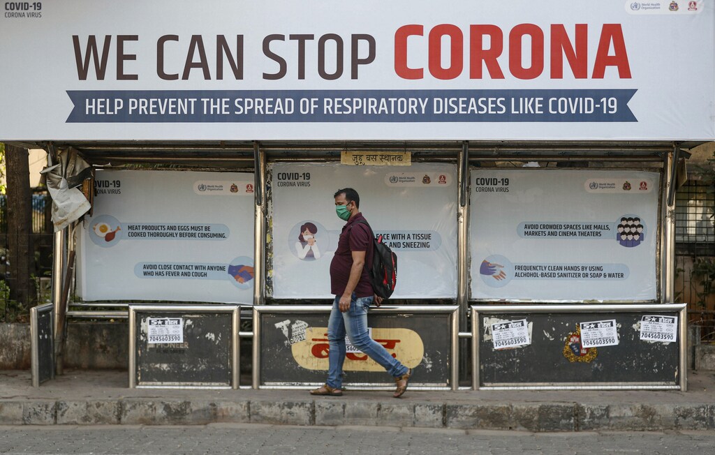 A man wearing a protective mask walks past a bus stop displaying preventive measures against the coronavirus in Mumbai, India, March 18, 2020. REUTERS/Francis Mascarenhas - RC2BMF9GGPRU
