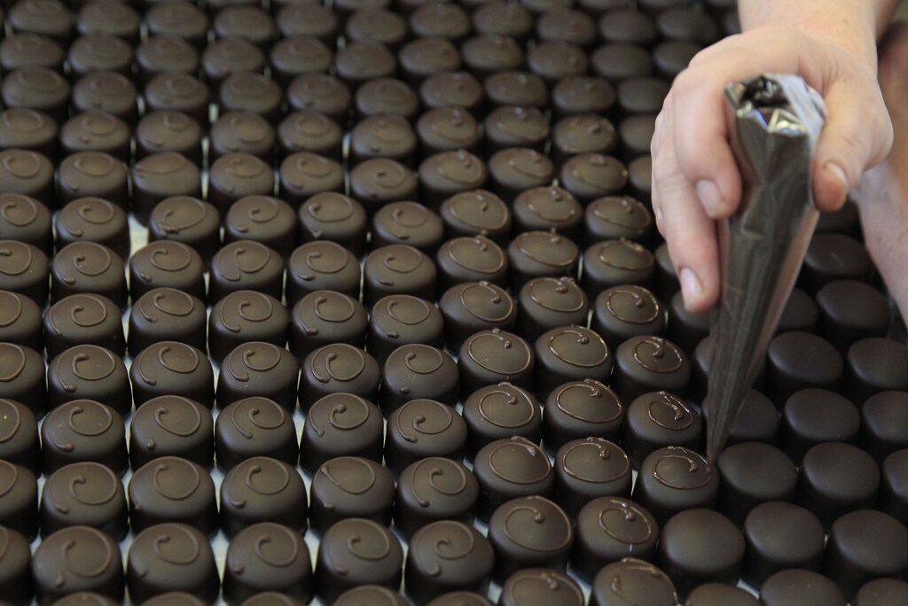 A woman decorates chocolate bon-bons at the manufacturing site of premium desserts maker Szamos Marcipan in Pilisvorosvar, Hungary, December 10, 2015. Hungarians could outspend last year's record on seasonal treats and Christmas fondants, giving some premium brands a hard time to keep up with strong demand. Picture taken December 10, 2015. REUTERS/Bernadett Szabo - RTX1ZYY9