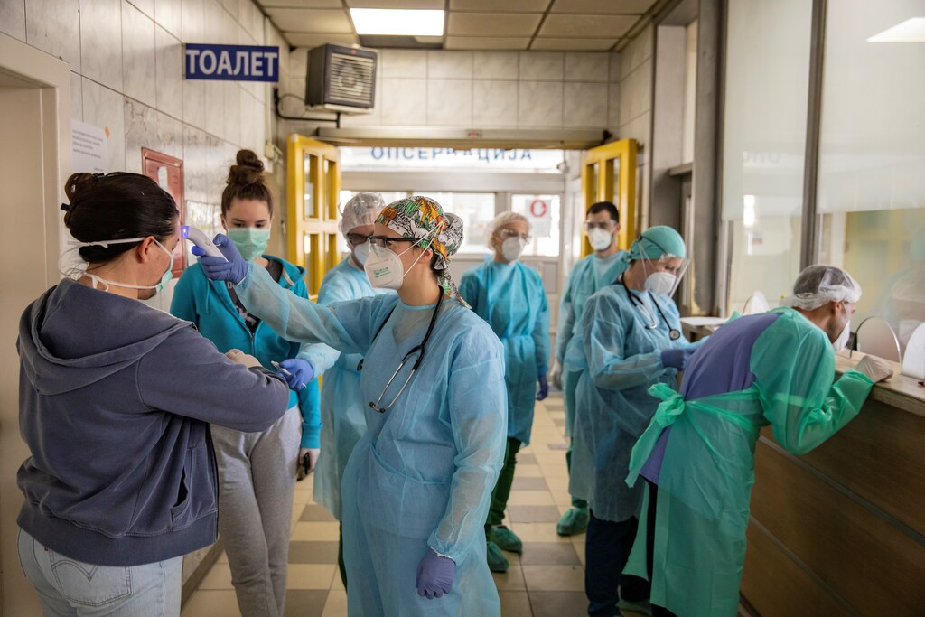 image of a medical worker uses a thermal scanner to measure the temperature of someone at a hospital in Belgrade, Serbia