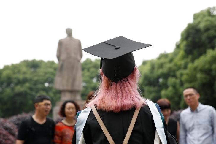 A student stands in front of the statue of Chinese leader Mao Zedong after her graduation ceremony at Fudan University in Shanghai, China June 23, 2017. REUTERS/Aly Song