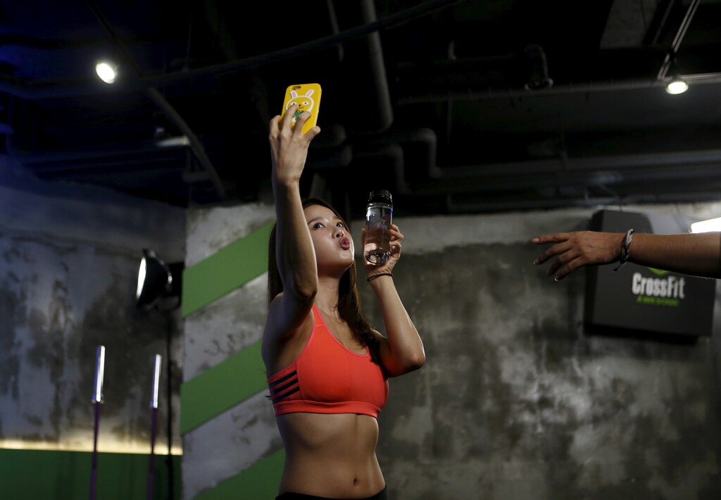 Ray Yang, a celebrity trainer, takes a selfie before the start of a workout session during TV program "The Body Show" at a gym in Seoul, September 19, 2015. Looks no longer centre only on the face in beauty-obsessed South Korea, where more women are hitting the gym to improve muscle tone and physical health. As the ideal of beauty evolves in a country that is a trendsetter in cosmetics and the pursuit of plastic surgery, women's fitness has become a growth business, say purveyors of health products, from diet supplements to dumb-bells."Women used to starve in order to lose weight. Now they exercise," said celebrity trainer Ray Yang, who leads a workout session during the Body Show, a weekly television event targeted at women that is now in its second season. Picture taken on September 19, 2015. REUTERS/Kim Hong-Ji - RTS5VJB