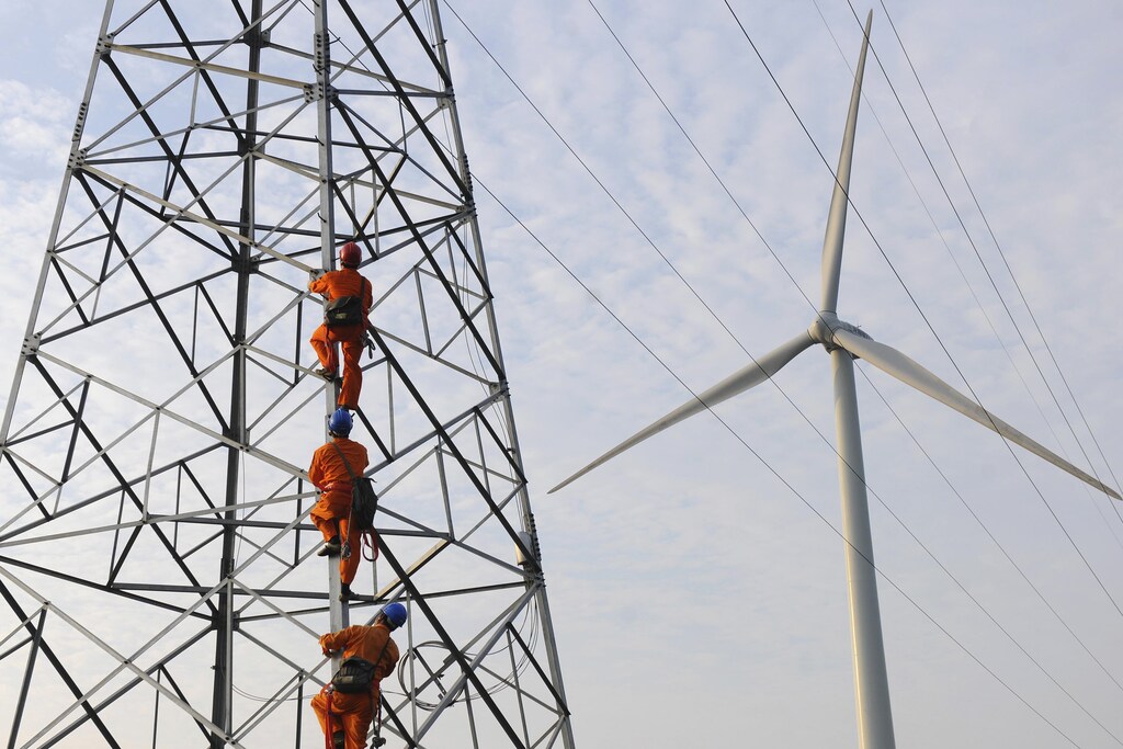 Employees climb up an electricity pylon next to a windmill to carry on a routine inspection at a wind power plant in Mingguang, Anhui province July 8, 2013. Picture taken July 8, 2013. REUTERS/China Daily (CHINA - Tags: BUSINESS ENVIRONMENT ENERGY TPX IMAGES OF THE DAY) CHINA OUT. NO COMMERCIAL OR EDITORIAL SALES IN CHINA - GM1E9790W6U01
