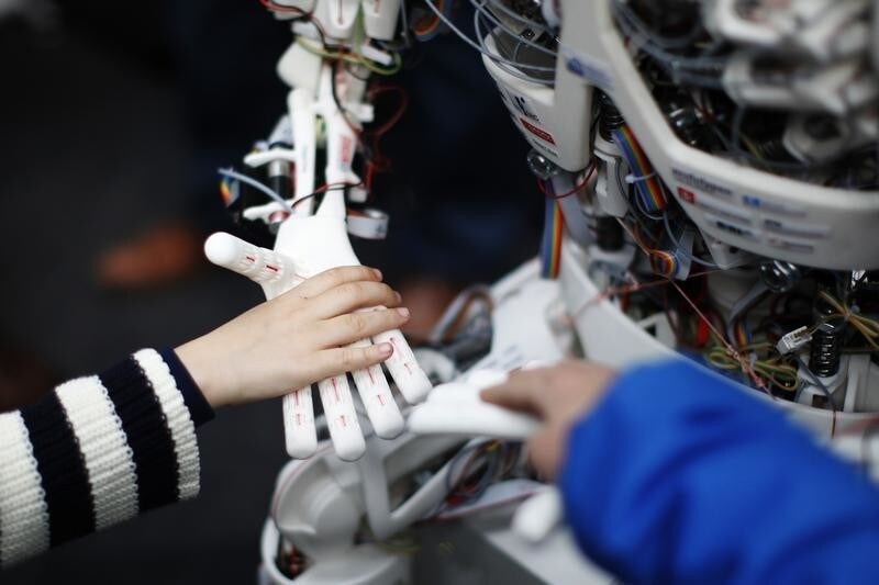 Children touch the hands of the humanoid robot Roboy at the exhibition Robots on Tour in Zurich, March 9, 2013. A project team composed of scholars and industry representatives developed the prototype of the tendon driven humanoid robot Roboy within nine months. Roboy was unveiled to the public today during the exhibition that is marking the 25th anniversary of the Artificial Intelligence Laboratory of the University of Zurich (AI Lab). REUTERS/Michael Buholzer (SWITZERLAND - Tags: SCIENCE TECHNOLOGY SOCIETY BUSINESS) - BM2E93916AH01