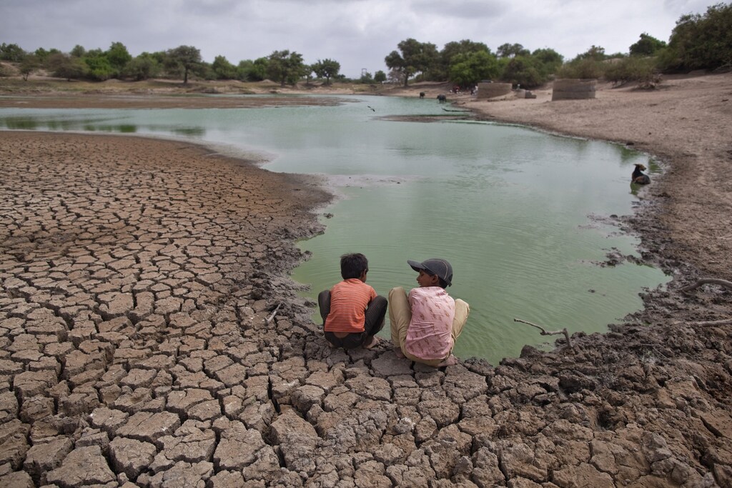 Children wash their hands in a partially dried-out natural pond at Badarganj village, in the western Indian state of Gujarat, August 5, 2012. Armed with the latest monsoon rainfall data, weather experts finally conceded this month that India is facing a drought, confirming what millions of livestock farmers around the country had known for weeks. Picture taken August 5, 2012. To match Feature INDIA-DROUGHT/ REUTERS/Ahmad Masood (INDIA - Tags: AGRICULTURE ENVIRONMENT TPX IMAGES OF THE DAY) - GM2E88D0G6501