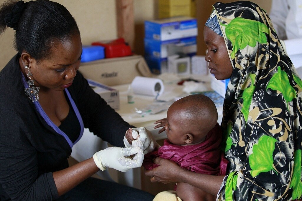 A clinic support staff takes blood sample from a child at a clinic operated by Doctors without Borders in Bagega village in northeastern state of Zamfara August 14, 2013. Picture taken August 14, 2013. REUTERS/Akintunde Akinleye (NIGERIA - Tags: HEALTH) - RTX12TC2