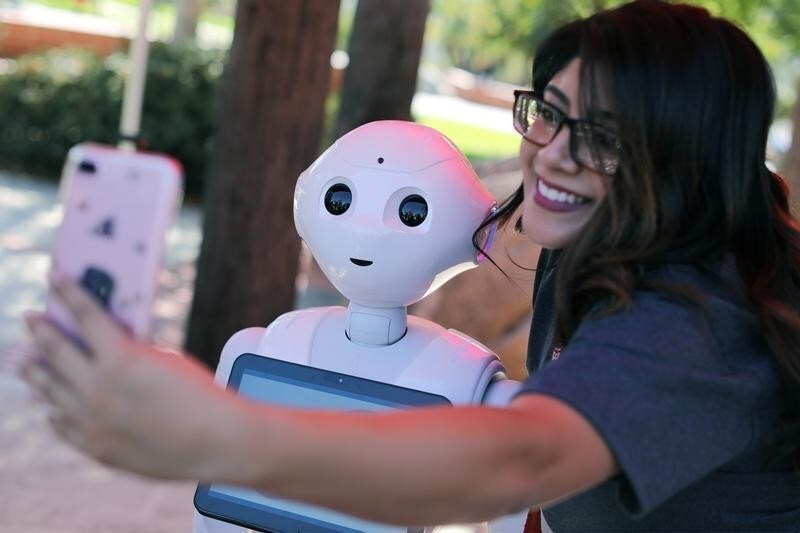 San Marcos student Amaris Gonzalez takes a selfie with "Pepper" an artificial Intelligence project utilizing a humanoid robot from French company Aldebaran and reprogramed as an assistant for students attending Palomar College in San Marcos, California, U.S. October 10, 2017. REUTERS/Mike Blake - RC1C5B9E1CA0