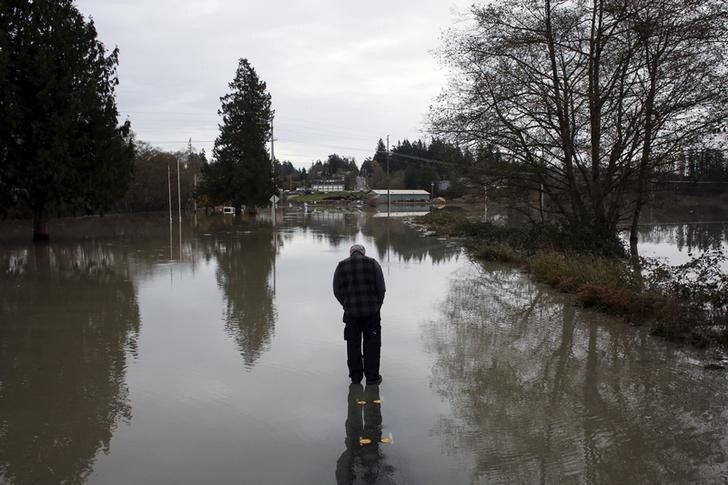 Andrew Culver observes the flooded waters of the Stillaguamish River, which overtook a roadway in Stanwood, Washington November 18, 2015. At least three people were killed and about 250,000 homes and businesses were without power in Washington state on Wednesday after a storm blew down trees and triggered mudslides, authorities said. REUTERS/David Ryder