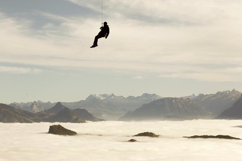 Fog covers the valleys behind as a man is abseiled from a cable car during an annual rescue exercise at the funicular to Mount Pilatus (2,128 m/6,982 ft) near Luzern November 9, 2011.