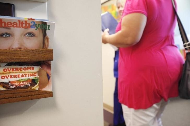 Carolyn Dawson, bariatric surgery patient walks by a copy of "health2you" magazine with a cover story on how to overcome overeating at the Rose Medical Center in Denver for her pre-op appointment five days before her procedure August 25, 2010. Dawson, weighing 296 pounds before the surgery hoped to lose around 150 pounds over the next year. REUTERS/Rick Wilking (UNITED STATES)