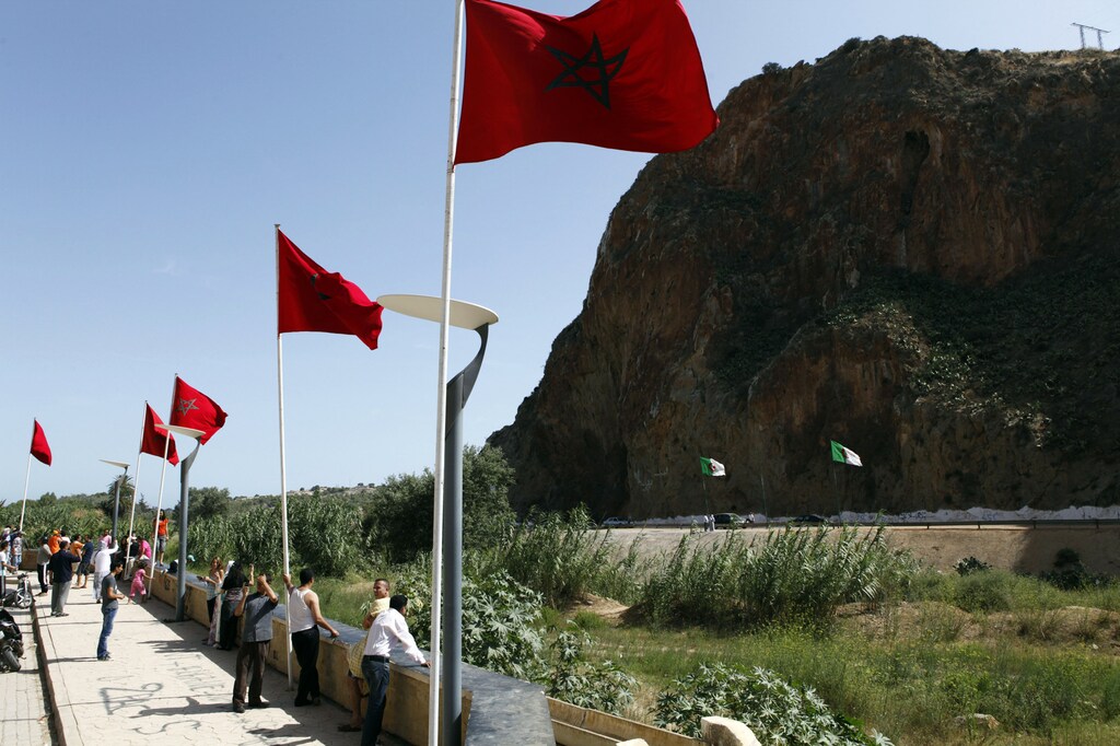People stand near a border post on the Algerian side of the Morocco-Algeria border in the north east of Morocco July 31, 2011