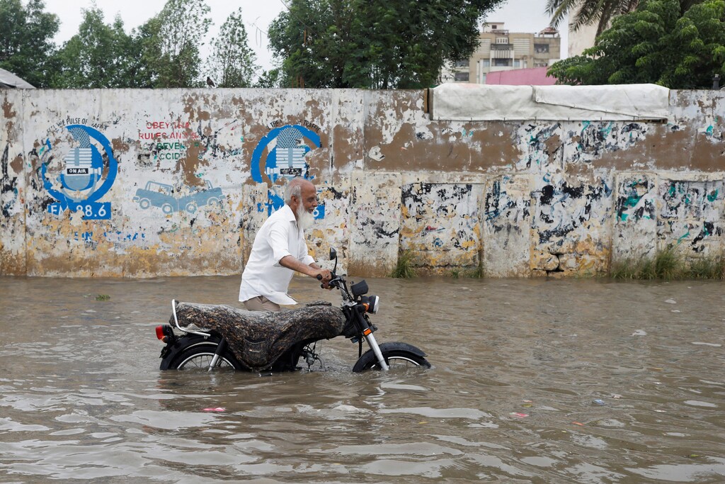 A man pushes his bike as he wades through a flooded road during the monsoon season in Karachi, Pakistan July 9, 2022. COP27: Climate reparations will help developing countries recover from climate disasters, such as floods and violent storms.