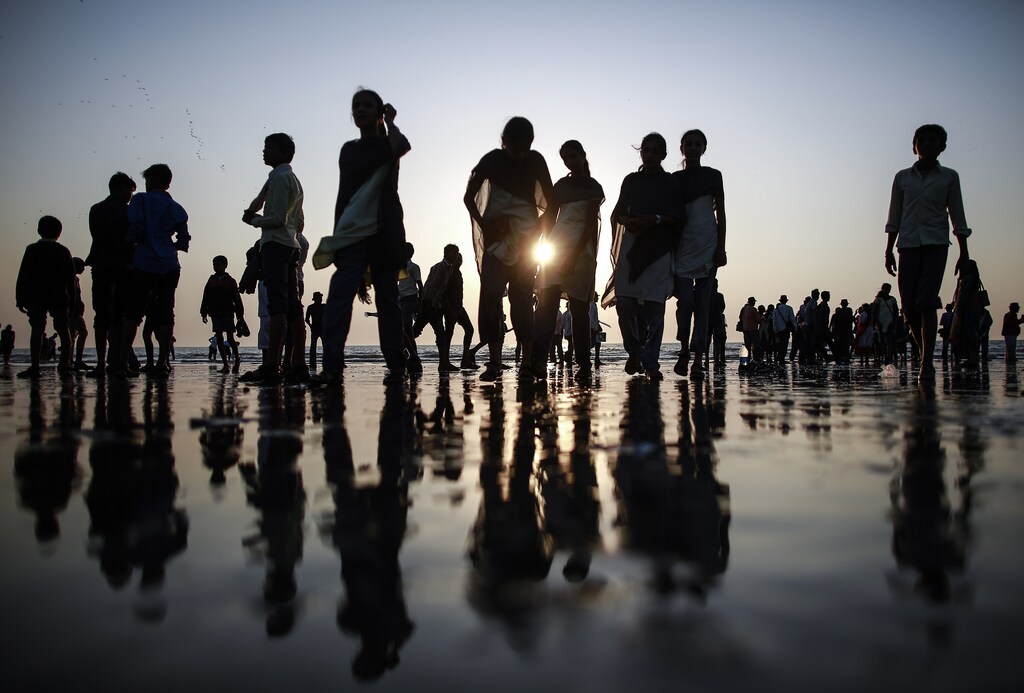 People are silhouetted as they walk on a beach along the shores of the Arabian Sea in Mumbai January 9, 2015