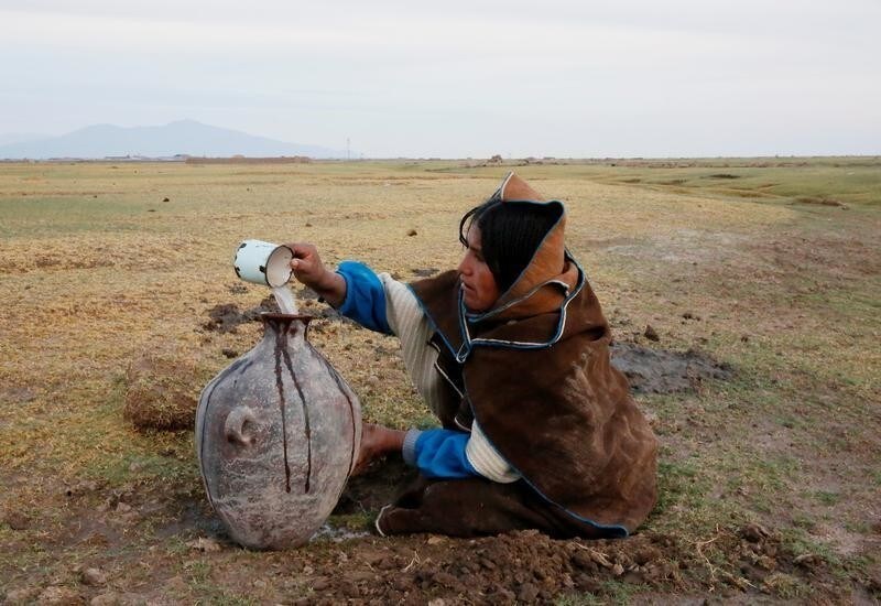 An Uru Chipaya woman pours water from a well into a jar in Chipaya , Bolivia, January 31, 2018. Picture taken January 31, 2018. REUTERS/David Mercado - RC16B0F79800
