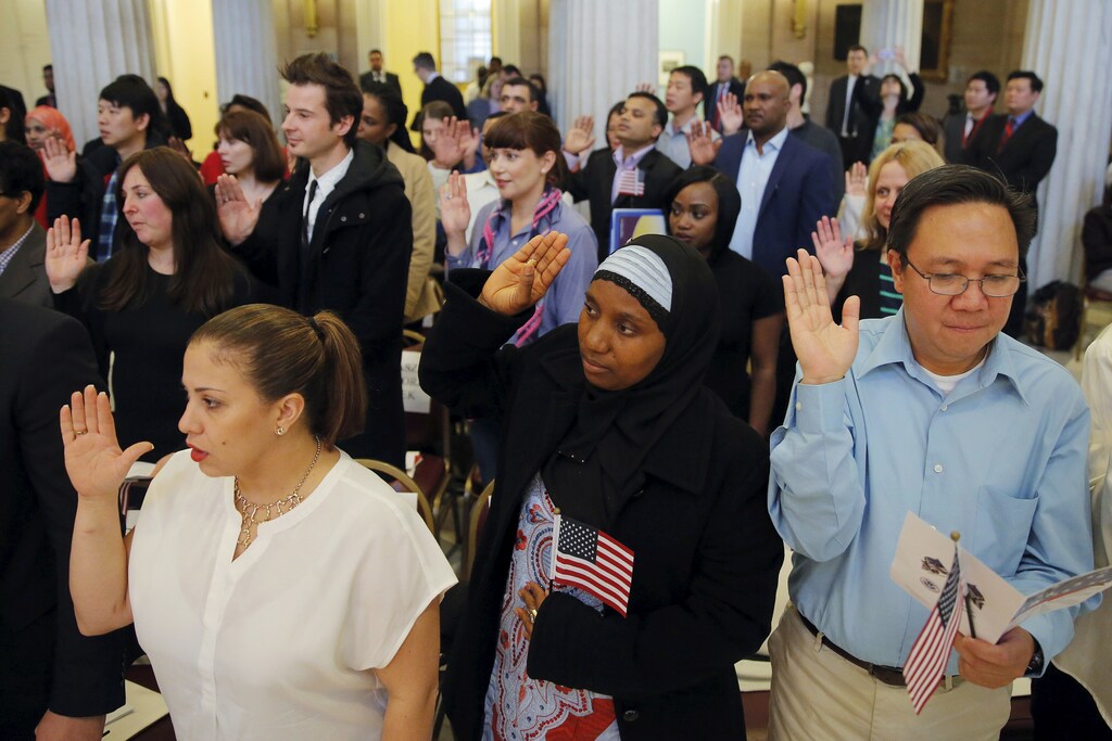 Isatu Barrie (C) raises her hand while taking the United States Oath of Citizenship during a naturalization ceremony in the Brooklyn borough of New York December 15, 2015. REUTERS/Lucas Jackson - RTX1YV2D