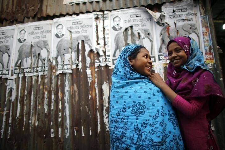 Girls play in front of torn election campaign posters ahead of Sunday's elections in Dhaka January 4, 2014. Nearly 60 polling stations in Bangladesh were set on fire and three people were killed on the eve of Sunday's election in which the ruling Awami League looks certain to prevail in a walkover as the main opposition party boycotts the poll. REUTERS/Andrew Biraj (BANGLADESH - Tags: POLITICS ELECTIONS SOCIETY)