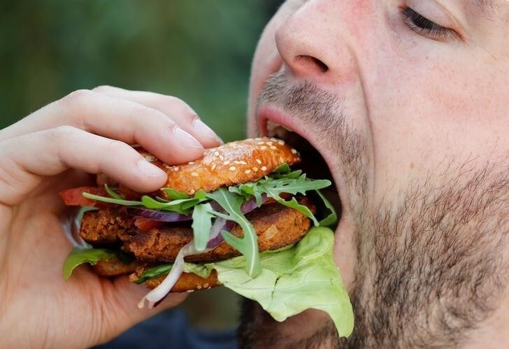 Max Kraemer, a 32-year-old geographer of the start-up "Bug Foundation" bites into a hamburger made of Buffalo worms (Alphitobius Diaperinus), that he created together with a business economist, during its premiere in a supermarket in Aachen, Germany, April 20, 2018. REUTERS/Wolfgang Rattay TPX IMAGES OF THE DAY