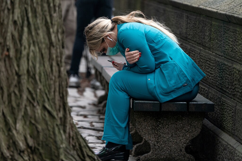 A healthcare worker sits on a bench near Central Park in the Manhattan borough of New York City, U.S., March 30, 2020. REUTERS/Jeenah Moon TPX IMAGES OF THE DAY - RC2NUF9VY5KU