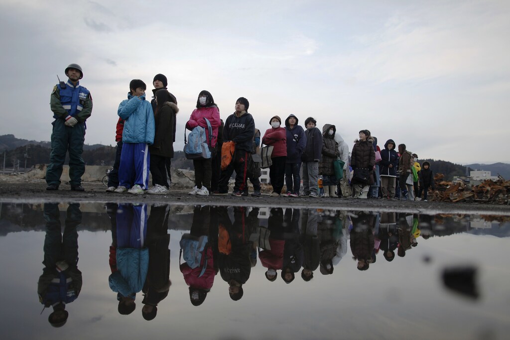 sunami victims wait in the line to receive aid more than two weeks after the area was devastated by a magnitude 9.0 earthquake and tsunami in a badly burnt area of Yamada town, Iwate Prefecture in northern Japan March 26, 2011.
