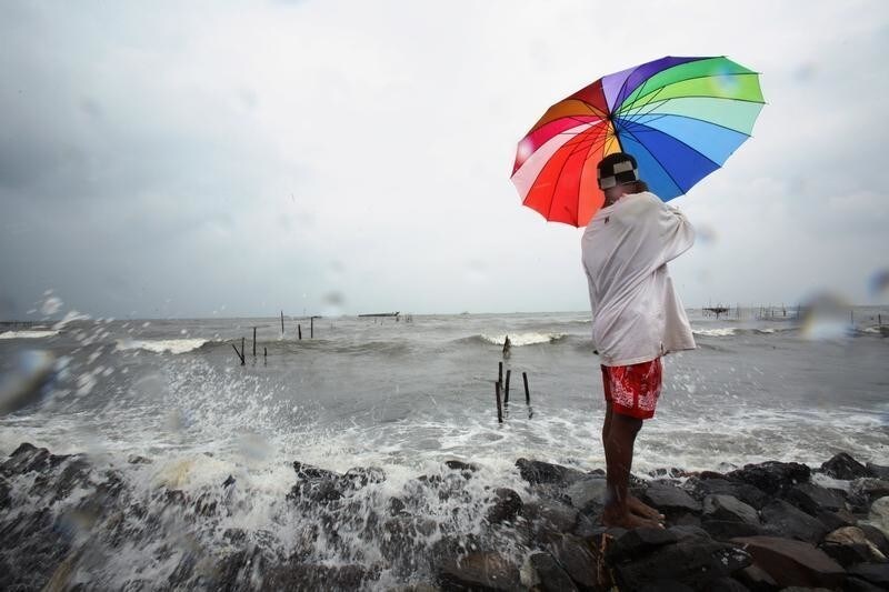 A fisherman holds an umbrella while watching his net as waves hit the Marunda beach in Jakarta February 1, 2007. Indonesia could lose about 2,000 islands by 2030 due to climate change, the country's environment minister said on Monday. A draft U.N. report due to be released in Paris on February 2 projects a big rise in temperatures this century and warns of more heat waves, floods, droughts and rising seas linked to greenhouse gases. REUTERS/Beawiharta (INDONESIA) - GM1DUNARXHAA