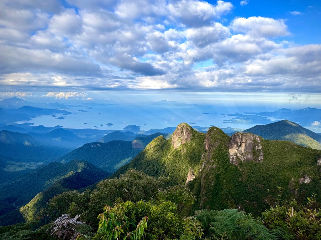 山々の向こうに見える海と空。ネイチャーポジティブ投資は、企業と地球環境の双方に利益をもたらします。