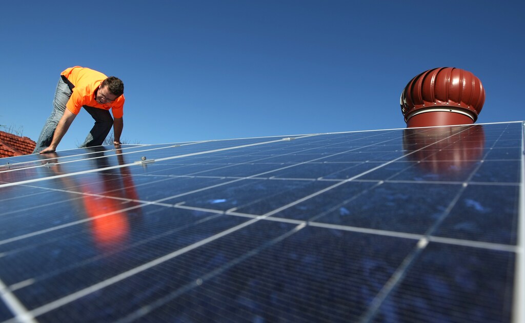 Solar system installer Thomas Bywater adjusts new solar panels on the roof of a house in Sydney August 19, 2009. REUTERS/Tim Wimborne (AUSTRALIA ENVIRONMENT ENERGY) - GM1E58J163L01