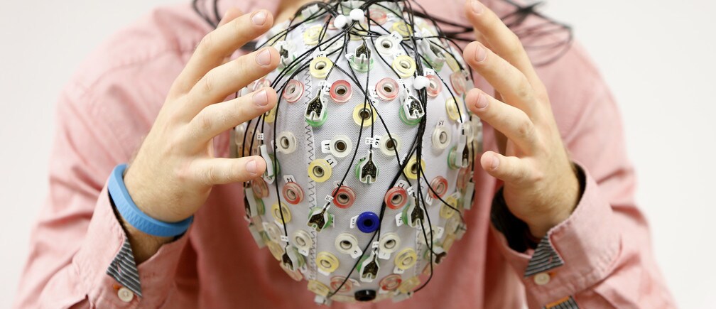 Test person Niklas Thiel poses with an electroencephalography (EEG) cap which measures brain activity, at the Technische Universitaet Muenchen (TUM) in Garching near Munich.