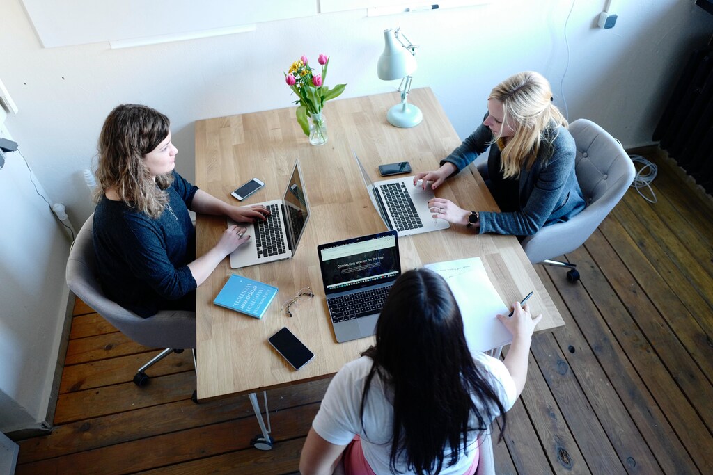 3 women sit in an office.