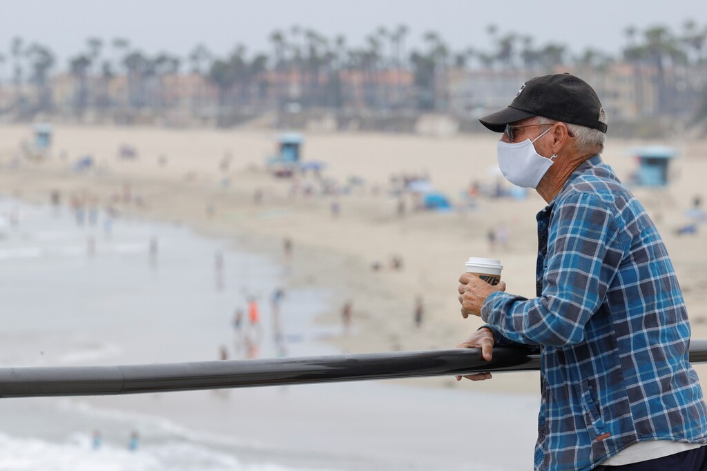 A man wearing a face mask looks out at the beach as the United States on Thursday passed a total of more than 4 million coronavirus infections during the global outbreak of the coronavirus disease (COVID-19) in Huntington Beach, California, U.S., July 23, 2020. REUTERS/Mike Blake - RC2AZH96X12I