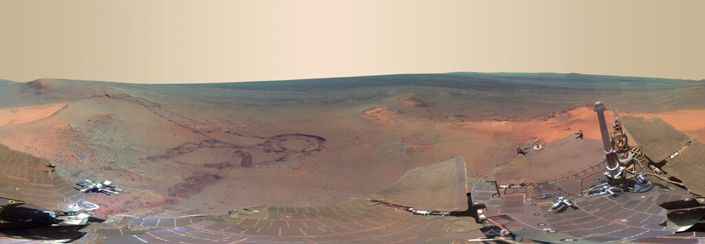 This NASA 360-degree panorama image of Mars made from some of 800 images sent from the Opportunity rover on Mars shown in exaggerated colors to highlight different surface features released on July 9, 2012, shows past tracks of Opportunity (L) as well as Opportunity's dust covered solar panels cross the image bottom and an interior wall of 20-kilometer Endeavour Crater just below the horizon and right of center. Now that the northern Martian winter is over, Opportunity is rolling again, this time straight ahead (north). The rover is set to investigate unusual light-colored soil patches as it begins again to further explore the inside of Endeavour, a crater that may hold some of the oldest features yet visited. REUTERS/NASA/JPL-Caltech/Cornell/Arizona State University/Handout (UNITED STATES - Tags: ENVIRONMENT SCIENCE TECHNOLOGY) FOR EDITORIAL USE ONLY. NOT FOR SALE FOR MARKETING OR ADVERTISING CAMPAIGNS. THIS IMAGE HAS BEEN SUPPLIED BY A THIRD PARTY. IT IS DISTRIBUTED, EXACTLY AS RECEIVED BY REUTERS, AS A SERVICE TO CLIENTS - GM1E87A0KPY01
