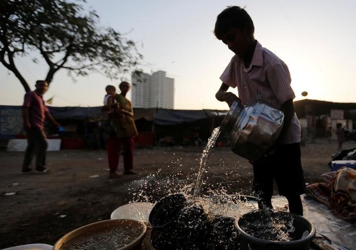 A boy fills a metal pitcher with water fetched from a communal tap at a slum in Mumbai, India, March 22, 2017. REUTERS/Danish Siddiqui