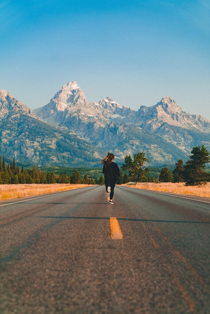 Person running along a road towards mountains