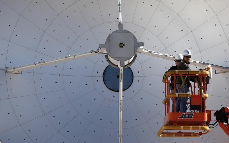 Workers prepare a parabolic antenna of the ALMA (Atacama Large Millimetre/Submillimetre Array) project at the El Llano de Chajnantor in the Atacama desert, some 1730 km
