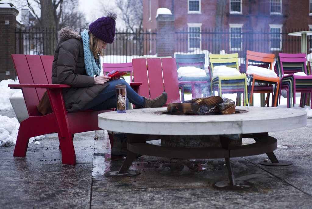 A woman reads a tablet beside a fire pit on cold winter evening outside the Science Center at Harvard University in Cambridge, Massachusetts February 18, 2015. REUTERS/Brian Snyder (UNITED STATES - Tags: ENVIRONMENT) - GM1EB2J0NXD02